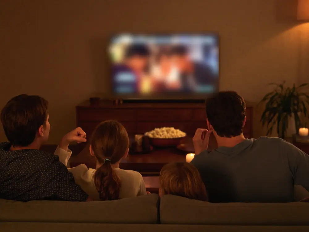 Family sitting together on a couch watching a movie at home